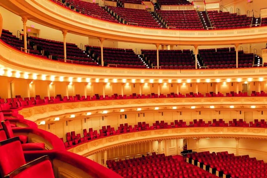 Teatro vuoto con sedili rossi e balconate eleganti.