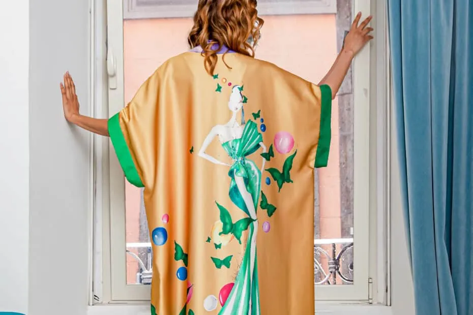 Donna in vestaglia colorata guarda fuori dalla finestra.