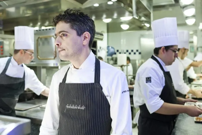 Cuoco professionista in una cucina ristorante affollata.