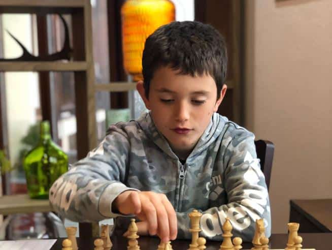 Bambino concentrato gioca a scacchi.