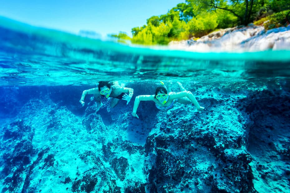 Due persone fanno snorkeling in acque cristalline.