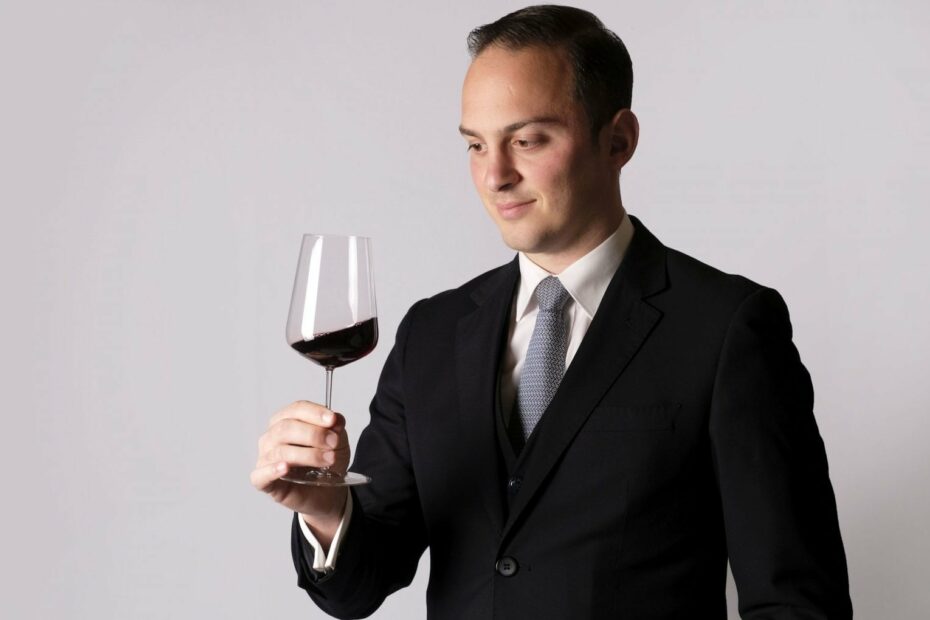 Uomo elegante valuta bicchiere di vino rosso.