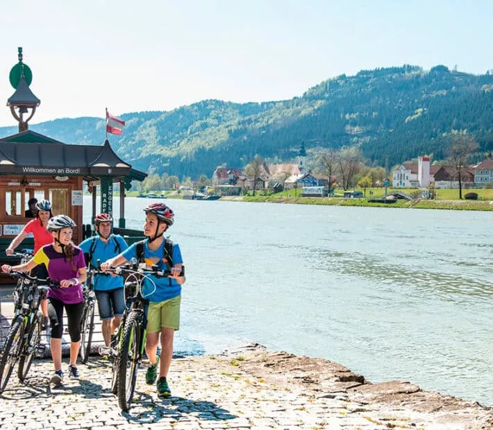 Ciclisti vicino al fiume in una giornata soleggiata.
