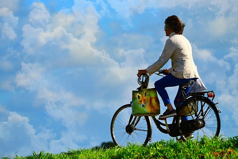 Persona in bicicletta su sfondo di nuvole.