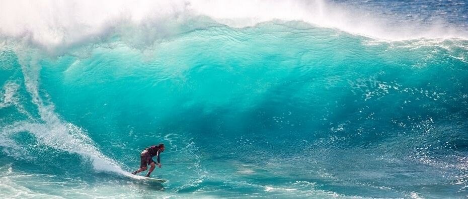 Surfista cavalca grande onda azzurra.
