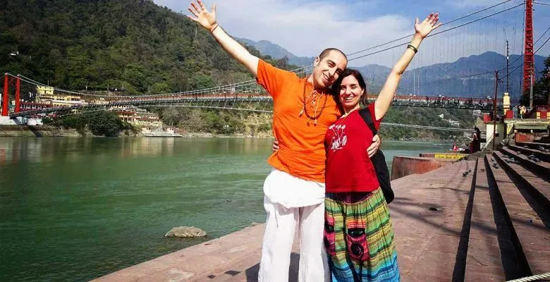 Coppia felice davanti a un fiume e ponte sospeso.