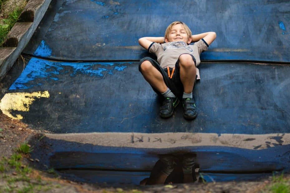 Bambino sorridente sdraiato su rampa di skatepark.