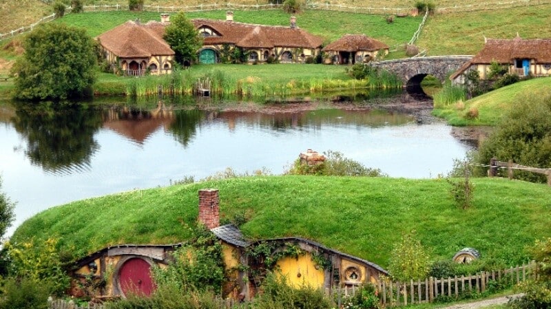 Case hobbit sul lago con erba verde.