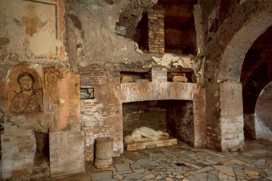 Interno antico con affreschi e caminetto in rovina.