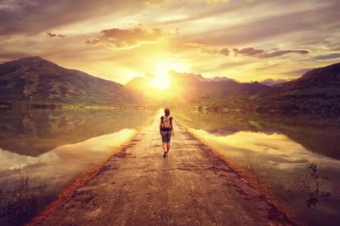 Donna passeggia al tramonto su strada lacustre.