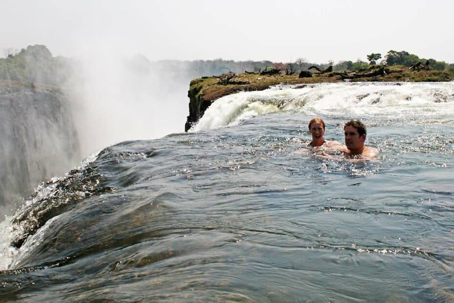 Due persone nuotano vicino a cascata.
