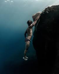 Sub in apnea vicino a una roccia sottomarina.