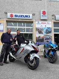 Due uomini davanti al concessionario Suzuki con moto.