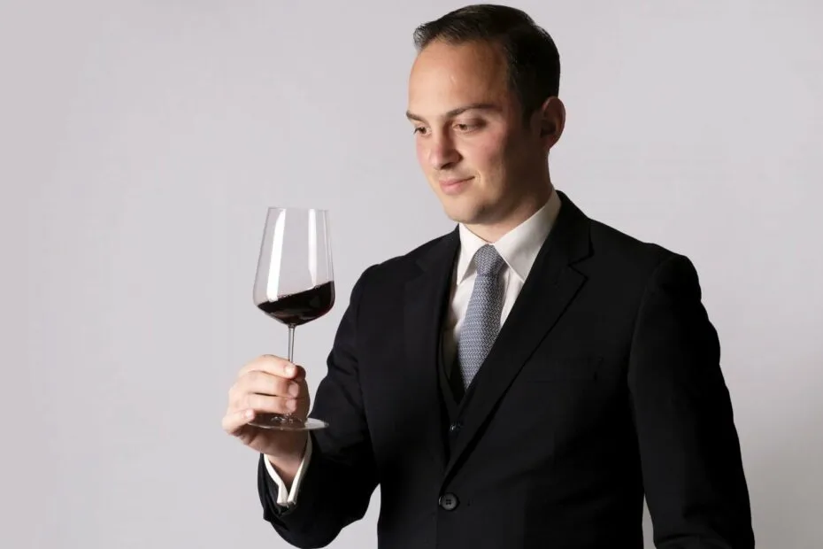 Uomo elegante valuta vino rosso.
