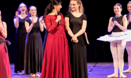 Due donne sorridenti sul palco durante una rappresentazione teatrale.