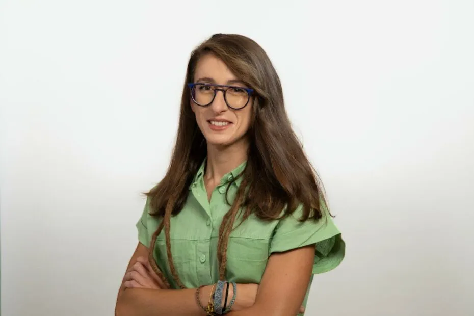 Donna sorridente con occhiali e camicia verde.