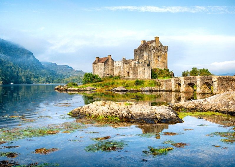 Castello scozzese antico riflettendosi nell'acqua.