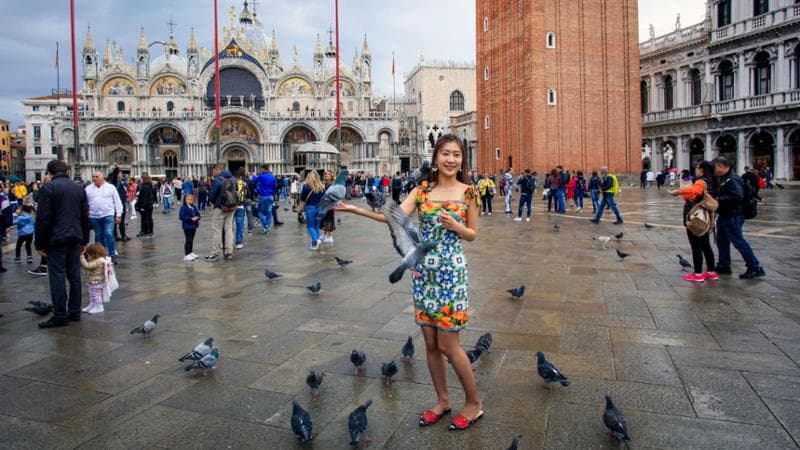 Turista con piccioni in Piazza San Marco.