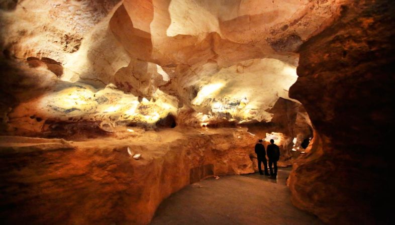 Persone esplorano una caverna illuminata.
