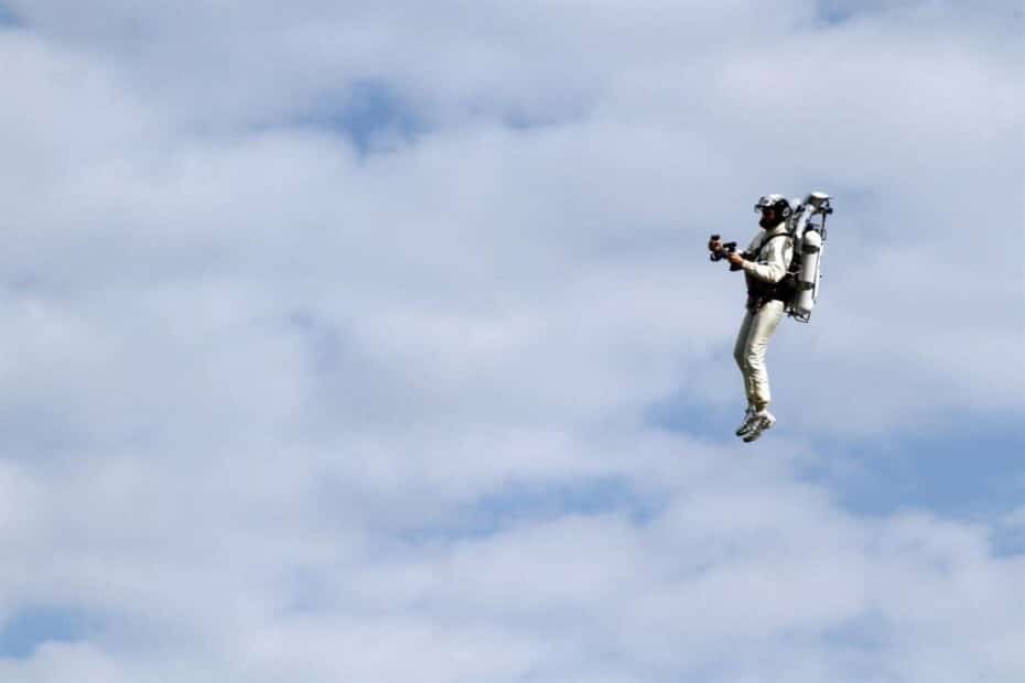 Uomo con jetpack vola nel cielo nuvoloso.